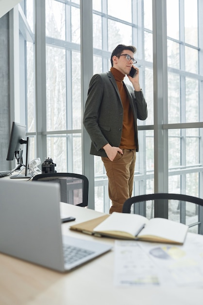 Young businessman talking on mobile phone while working at modern office