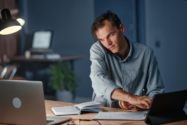 Young businessman talking on a smartphone and using a digital tablet