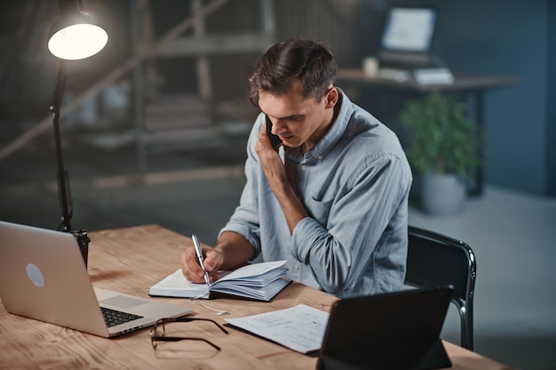 Young businessman talking on a smartphone and using a laptop