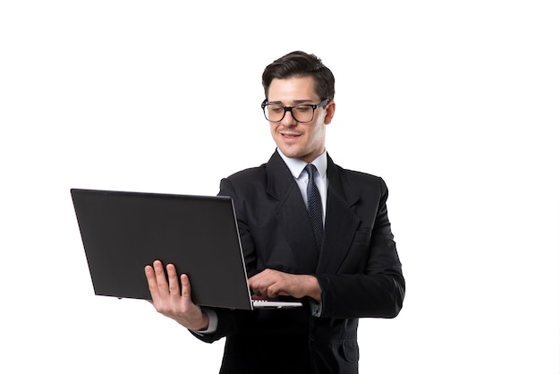 Young businessman in tie and black suit using laptop, isolated on white