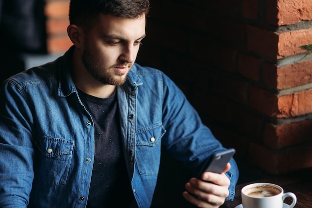 Young businessman use a phone in cafe while he use a laptop.