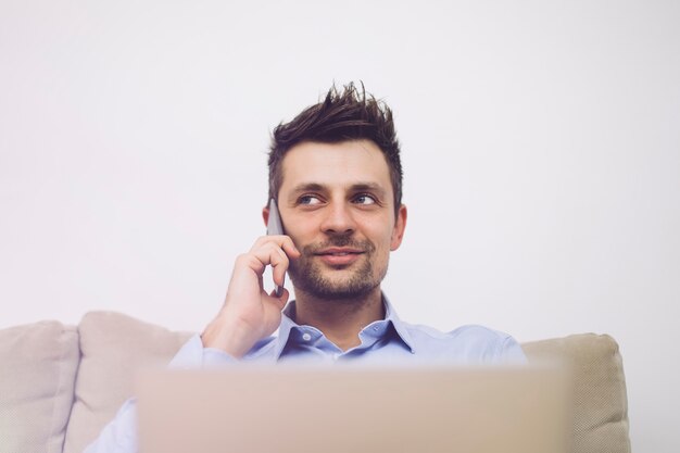 Young businessman using mobile phone and working on laptop