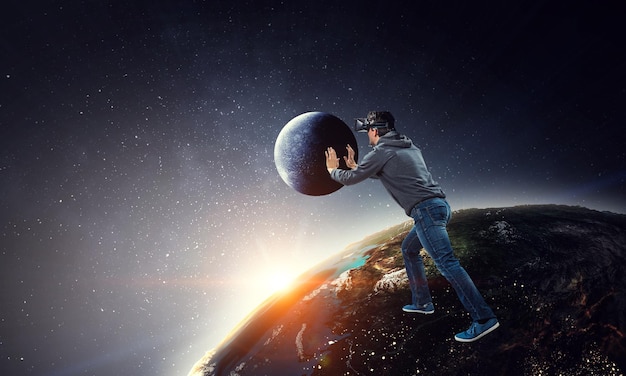 Young businessman in VR glasses rolling the Earth. Mixed media