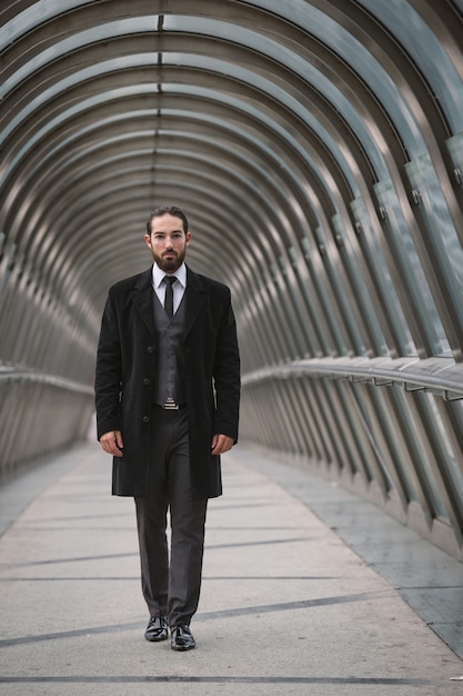 Young businessman walking on futuristic pedestrian bridge at the Defense District. Paris, France. 