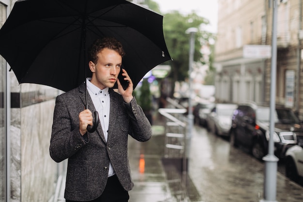 Young businessman walking in the rain