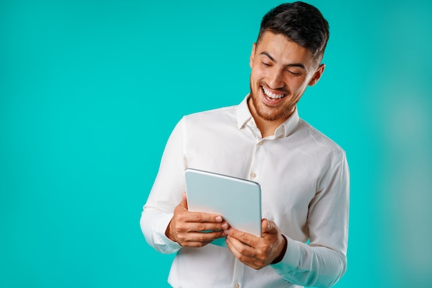 Young businessman wearing white shirt holds digital tablet against green