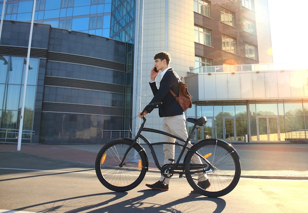 Foto giovane uomo d'affari con bicicletta e smartphone sulla strada della città.