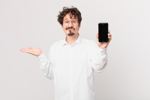 Young businessman with a cell feeling puzzled and confused and doubting