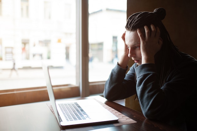 Young Businessman with dreadlock having doing his work in cafe with laptop.