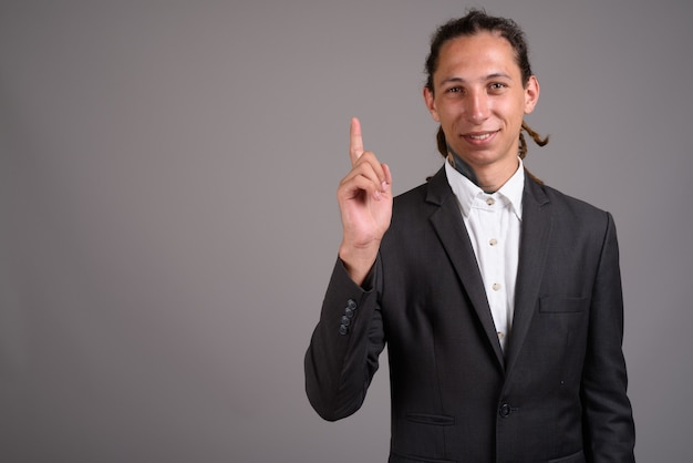 Young businessman with dreadlocks against gray background