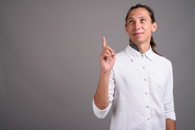 Giovane uomo d'affari con i dreadlocks su sfondo grigio