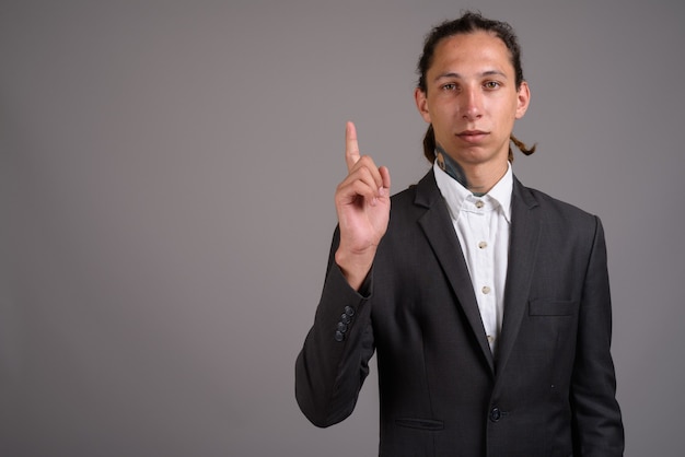 Young businessman with dreadlocks against gray background