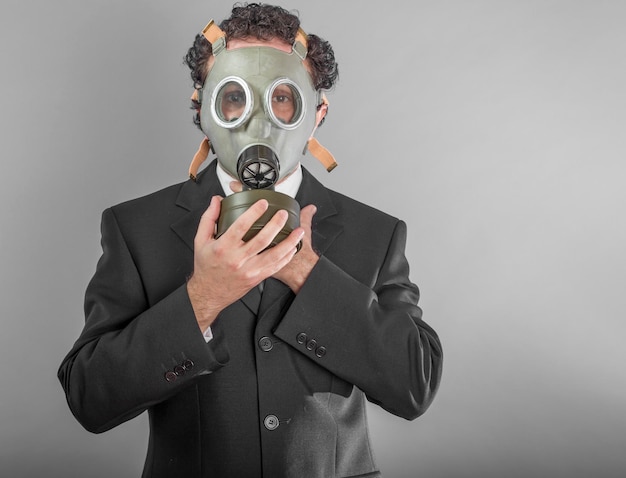 young businessman with gas mask over grey background