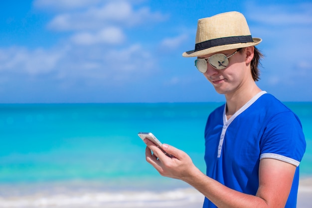 Young businessman with his phone on beach vacation