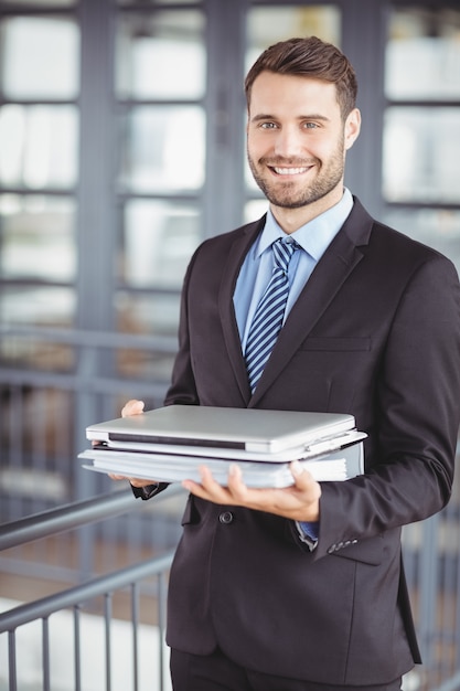 Giovane uomo d'affari con il computer portatile e documenti all'ufficio