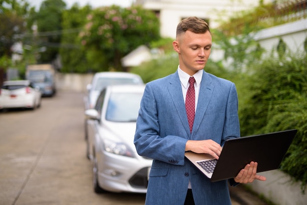 Young businessman with laptop in the streets outdoors