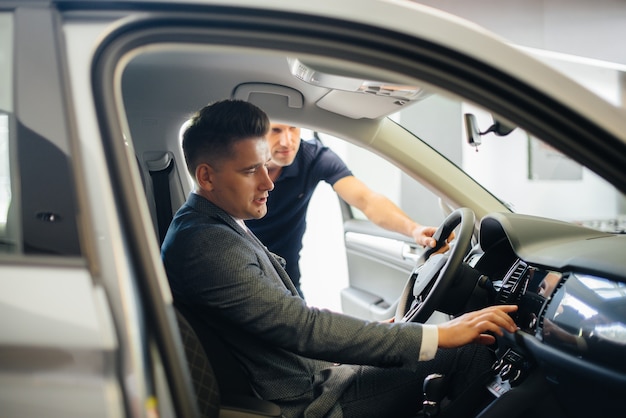 Foto un giovane uomo d'affari con un venditore guarda una nuova auto in una concessionaria di automobili