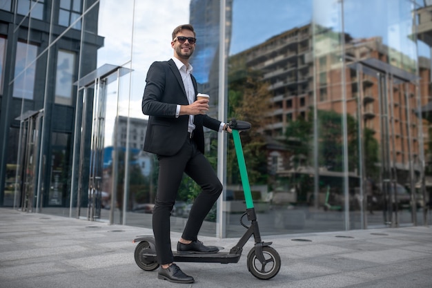 Young businessman with the scooter in the street