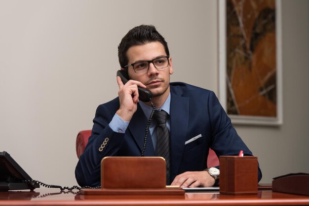 Young Businessman Working At His Computer While Talking On The Phone