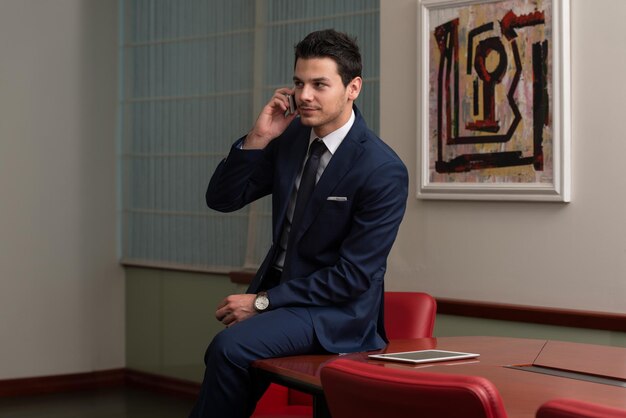 Young Businessman Working At His Computer While Talking On The Phone