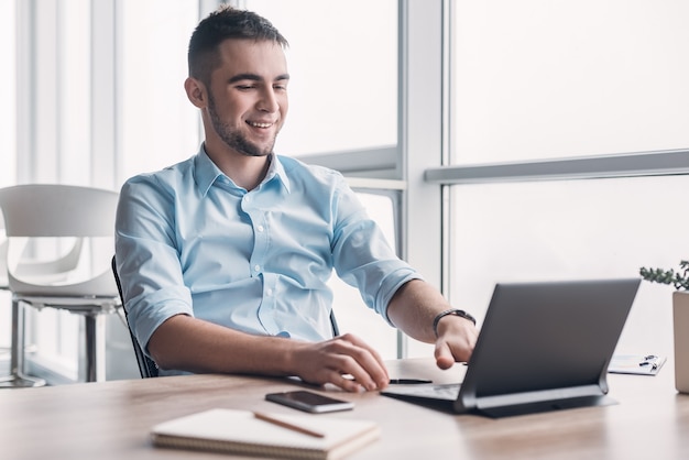 Young businessman working on his laptop in spacious bright office