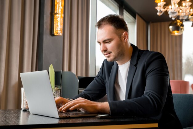 호텔에있는 현대적인 카페에서 노트북에서 일하는 젊은 사업가