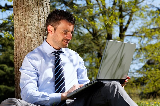 Young businessman working on laptop in a park