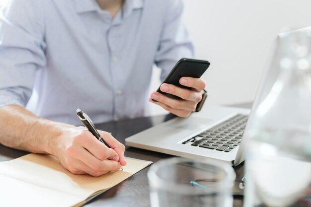 Young businessman working in office, using smartphone and laptop