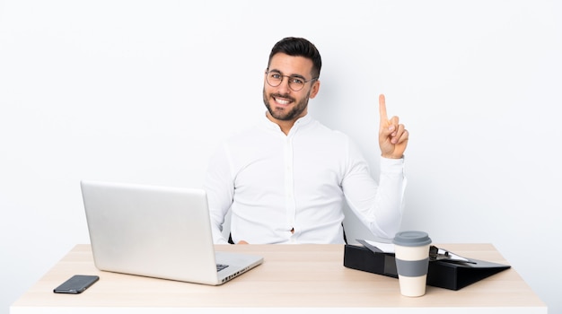 Young businessman in a workplace showing and lifting a finger in sign of the best