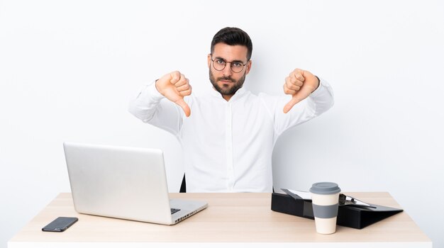 Young businessman in a workplace showing thumb down