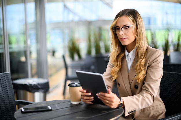 Young businesswoman on a coffee break. Using tablet computer.