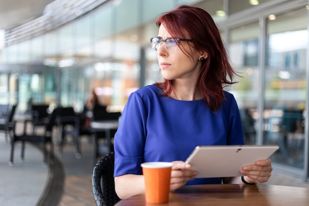 Young businesswoman on a coffee break. Using tablet computer.