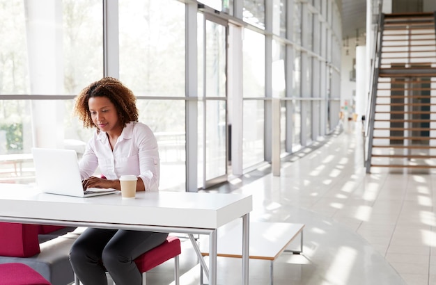 Photo young businesswoman at a desk working on her laptop