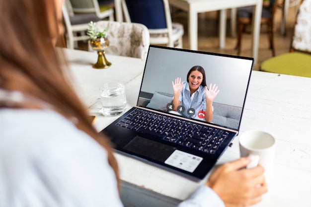 Young businesswoman drinking coffee and using laptop in cafe