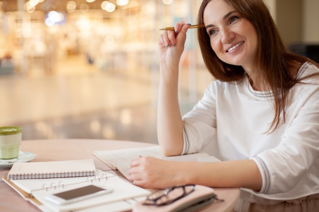 Young businesswoman in eyeglasses planning and writing down the daily schedule with in agenda