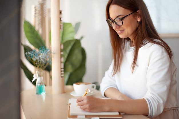 Young businesswoman in eyeglasses planning and writing down the daily schedule with in agenda