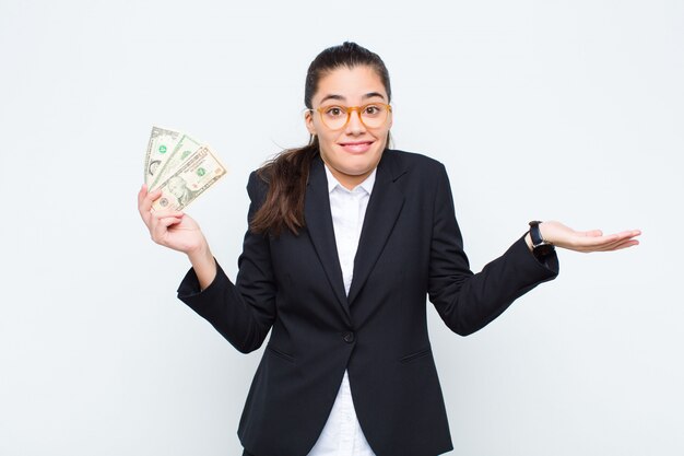 Young businesswoman feeling puzzled and confused, doubting, weighting or choosing different options with funny expression with banknotes with bills