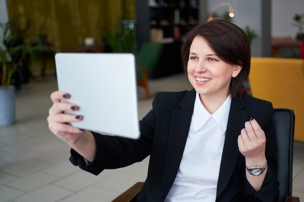 Young businesswoman having video call with tablet during cofe break