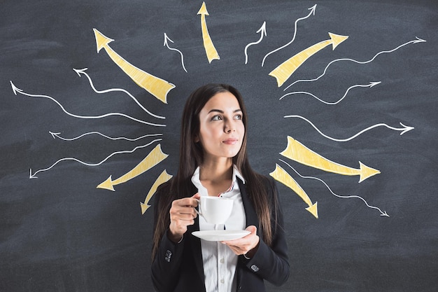 Photo young businesswoman holding coffeu cup with drawn arrows over her head