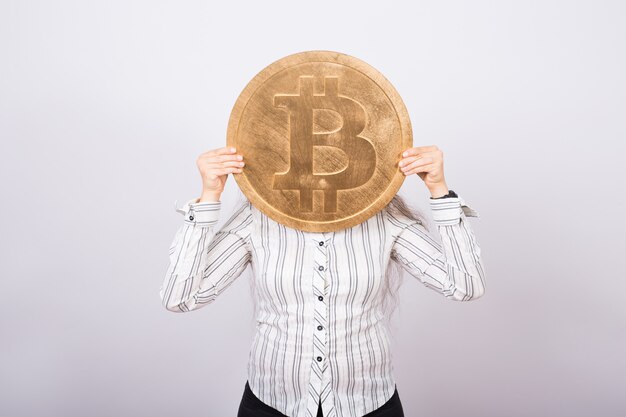 Young businesswoman holding a golden bitcoin