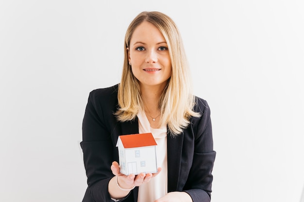 Young businesswoman holding miniature house model over white background