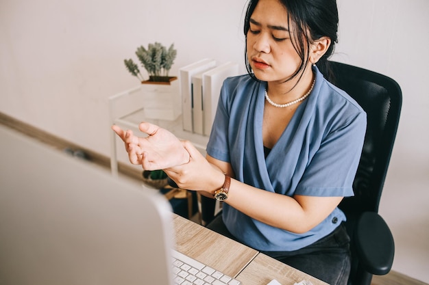 Young businesswoman holding painful wrist caused by prolonged work on the computer