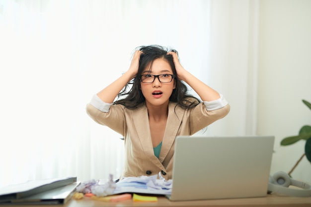 A young businesswoman is looking stressed as she works at her computer. Horizontal shot.