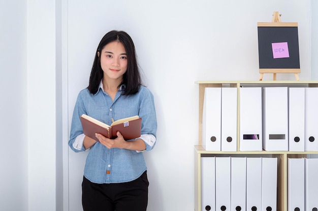 Young businesswoman is standing and writing down the details of his work at the office