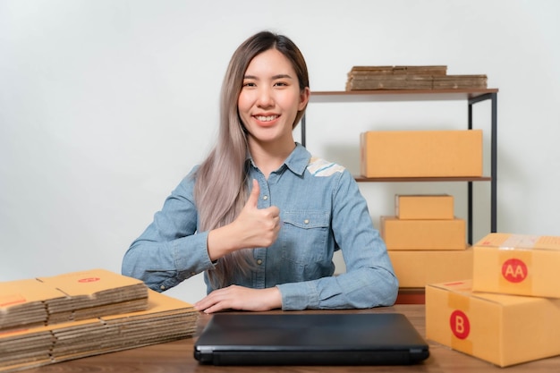 A young businesswoman is very happy after checking her email through her laptopOnline sellers are packing products into parcel boxes