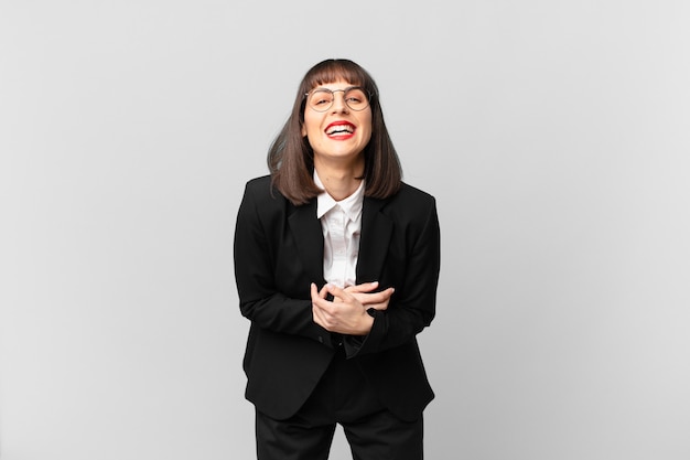 Young businesswoman laughing out loud at some hilarious joke, feeling happy and cheerful, having fun