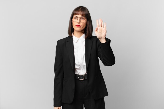 Young businesswoman looking serious, stern, displeased and angry showing open palm making stop gesture