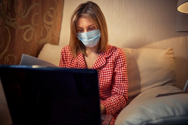 Young businesswoman in a medical protective mask works from home