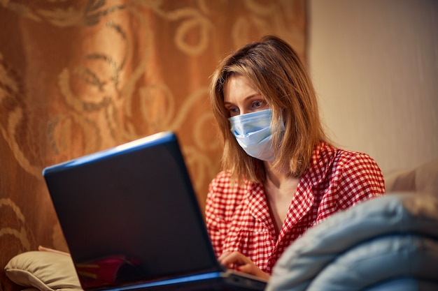 Young businesswoman in a medical protective mask works from home