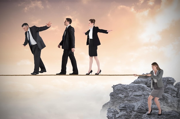 Young businesswoman pulling a tightrope for business people against rocky landscape